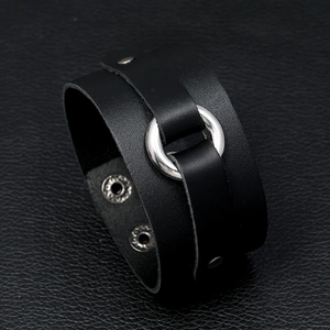 Close-up of black punk leather wristband with silver metal ring and snap button closure