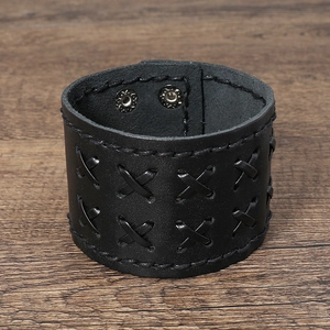 Macro detail of black leather cuff with cross stitching and metal snap buttons