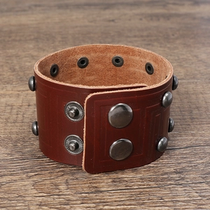 Dettaglio di un bracciale largo in pelle marrone retrò con borchie in metallo