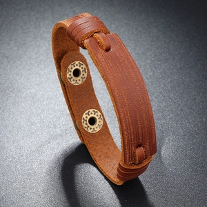 Macro detail of brown leather bracelet showing rustic texture and bronze snap buttons