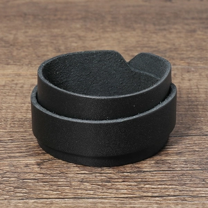 Close-up detail of double-layered black leather bracelet on rustic wood surface