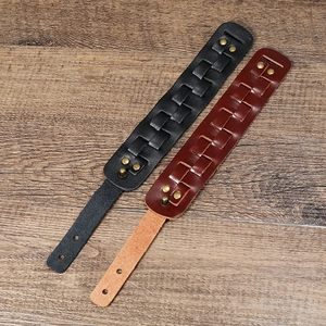 Detail of layered leather bracelets with braided texture and bronze metal rivets