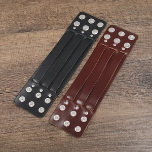 Detail of black and brown leather wide cuffs with metallic studs and snap buttons