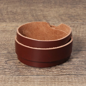 Detail view of double-wrap brown leather bracelet with natural texture on dark wood surface