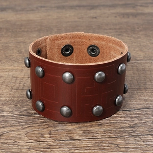 Dettaglio di bracciale largo in pelle marrone con due file di rivetti vintage in argento