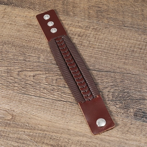 Bracelet en cuir marron tressé avec boutons-pression en métal sur table en bois