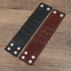 Detail of vintage wide leather bracelets with hand-woven X pattern and adjustable metal snaps