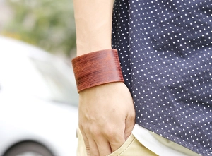 Detail of wide reddish-brown leather cuff bracelet with brushed texture on wrist