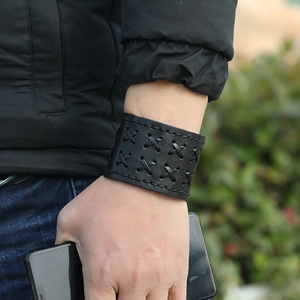 Close-up of black leather wide bracelet with cross-stitch detailing and punk style