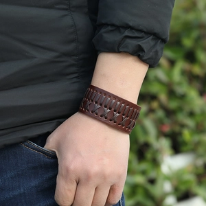 Close-up of wide hand-woven brown leather bracelet featuring cross-stitch braided design