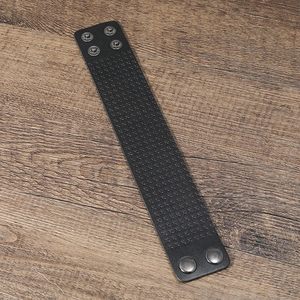 Detail showing the embossed cross texture and metal snap fasteners on black leather wristband