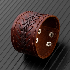 Macro view of brown braided leather cuff bracelet with adjustable silver metal snaps