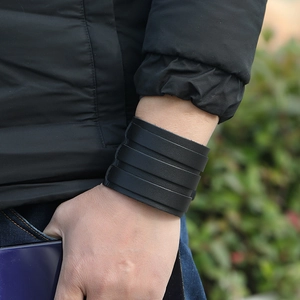Detail of wide black multi-layer leather cuff bracelet on wrist showing punk rock texture