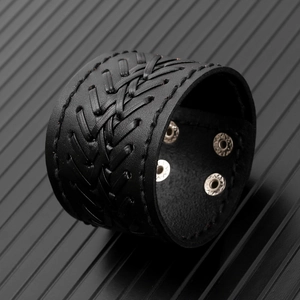 Close-up of black braided leather wide bracelet with adjustable silver metal snap buttons