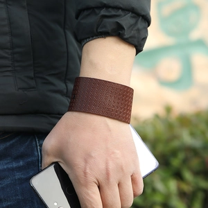 Detail view of a vintage brown leather wide bracelet with textured cross-stitch pattern