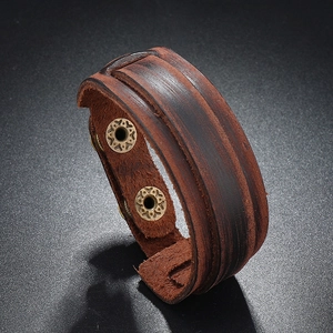 Close-up of vintage brown layered leather bracelet with engraved bronze snap buttons