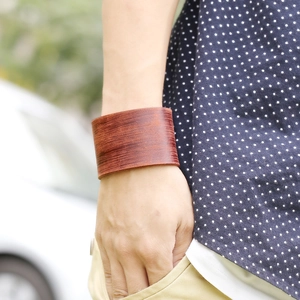 Retro wide dark brown leather bracelet with brushed texture worn on a wrist outdoors
