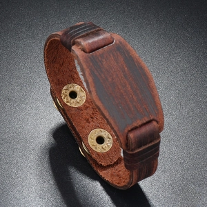 Macro detail of dark brown leather punk bracelet with decorative brass snap buttons