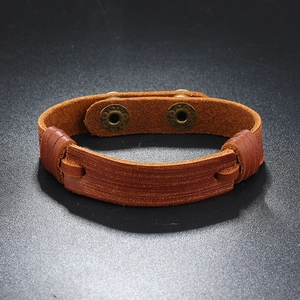 Macro detail of dark brown multilayer leather bracelet with bronze snaps and braided edges