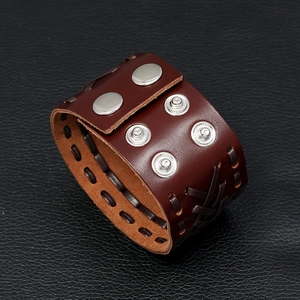 Close-up of vintage brown leather bracelet with metal snap buttons and woven details