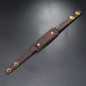 Close-up of vintage brown leather bracelet with golden studs and bronze snap fastener