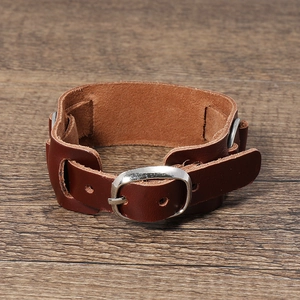 Primo piano di un ampio bracciale punk in pelle marrone scuro con fibbia in metallo regolabile