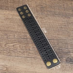 Retro black woven leather cuff bracelet with bronze adjustable snaps on wood background
