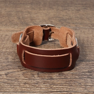 Dettaglio del bracciale punk in pelle marrone con fibbia in argento su legno scuro