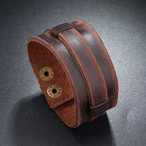 Detail of dark brown layered leather bracelet featuring vintage metallic snap buttons