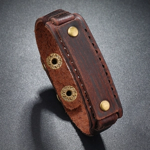Detail of dark brown leather bracelet with vintage brass rivets and stitching
