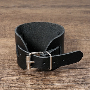 Détail d'un large bracelet en cuir noir vintage avec boucle ardillon en métal argenté