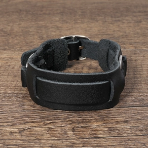 Dettaglio del bracciale multistrato in pelle nera con fibbia in metallo argento su legno