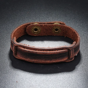 Detail of vintage brown leather bracelet with engraved bronze metal snap fasteners