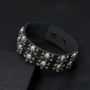 Detail view of punk leather bracelet featuring double rows of metal skull studs and buttons