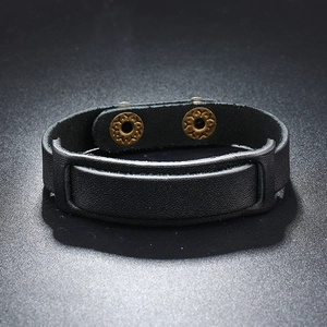 Detail of black leather punk bracelet featuring vintage bronze snaps and layered design