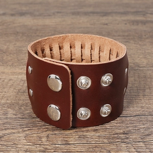 Vue détaillée d'un large bracelet en cuir marron avec des boutons-pression en métal argenté
