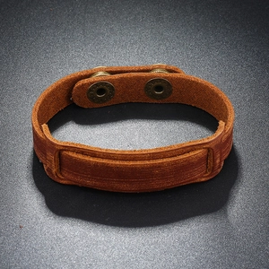 Detail view of a vintage brown leather wide bracelet with bronze double snap button closure