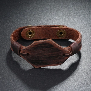 Dettaglio del bracciale vintage in pelle marrone con decoro esagonale e bottoni a scatto