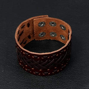 Detail of vintage brown leather bracelet showing woven texture and six metal snap buttons