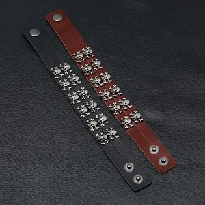 Macro detail of punk leather bracelets with double rows of vintage metal skull studs