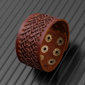 Dettaglio del bracciale in pelle intrecciata marrone con occhielli in metallo regolabili