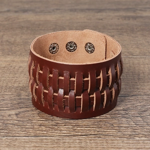 Détail d'un large bracelet en cuir tressé marron foncé avec trois boutons-pression