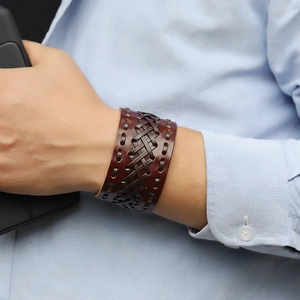 Close-up of a wide braided brown leather bracelet for men on a wrist with stitching detail