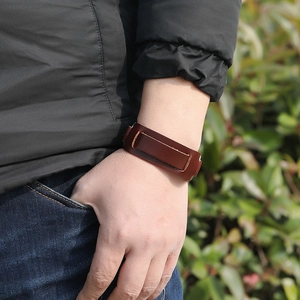 Dettaglio di un ampio bracciale in pelle marrone scuro con cinturini a strati e opachi