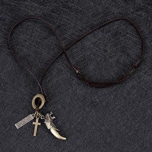 Détail du collier pendentif dent de loup vintage avec croix en bronze et cuir