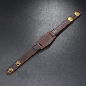 Detail of vintage brown leather bracelet showing natural texture and bronze snap buttons