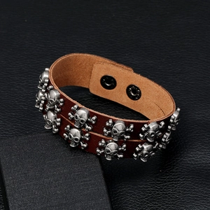 Detail view of punk style double-row skull studs on a brown leather bracelet for men