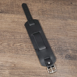 Gros plan d'un bracelet punk en cuir noir avec boucle argentée sur fond en bois