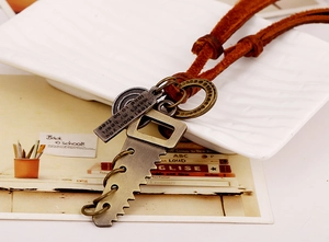 Macro detail of retro punk saw pendant with engraved metal tag and brown leather cord