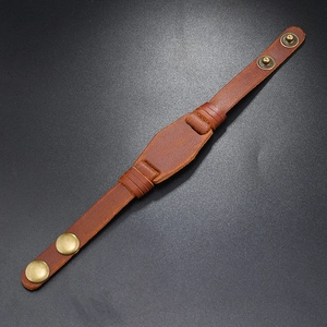 Detail view of brown braided leather bracelet with vintage bronze snap buttons